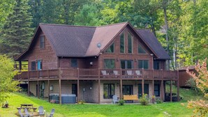Un'ampia casa in legno con un balcone, una terrazza e uno stagno di fronte.