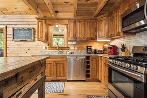 Cocina de estilo cabaña de madera con lavavajillas integrado, estufa y radio antigua.