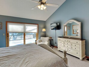Une chambre à coucher comprenant un lit, une commode, un téléviseur et un ventilateur de plafond.