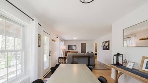 A modern living room with a large dining table, a sofa, and a TV.