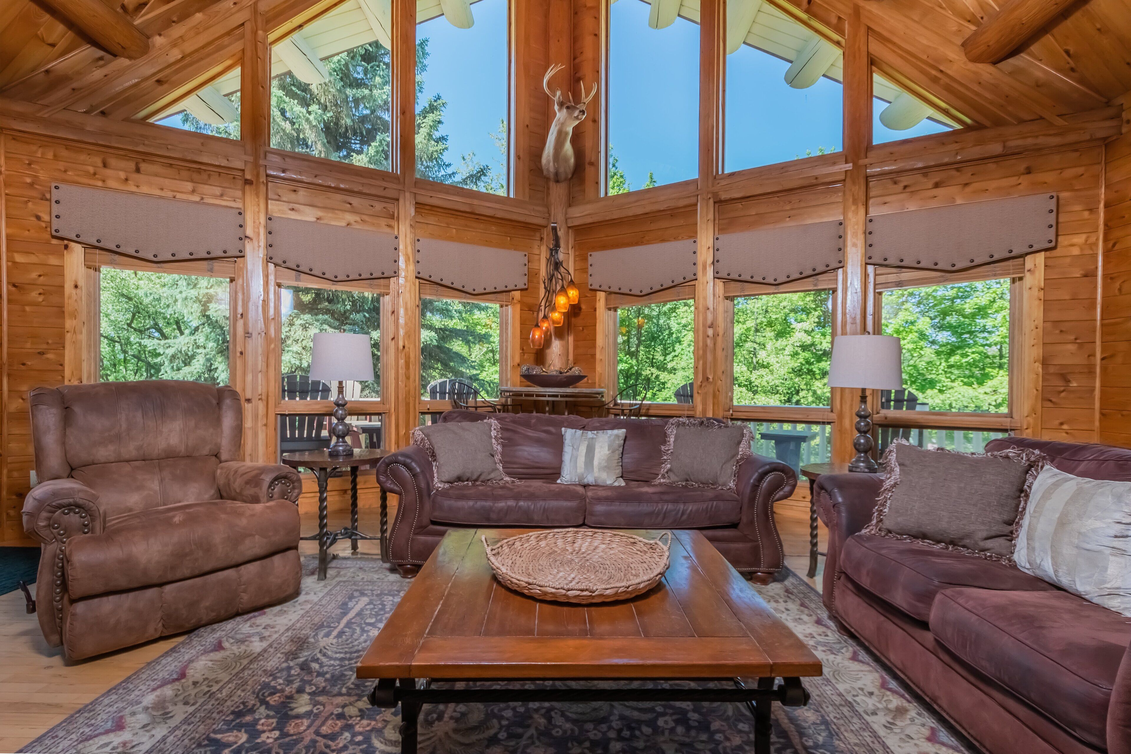 A wooden interior with a leather sofa, armchair, and a table with a woven basket.