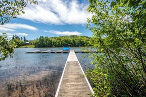 A wooden dock extending into a calm lake with a boat docked at the end.
