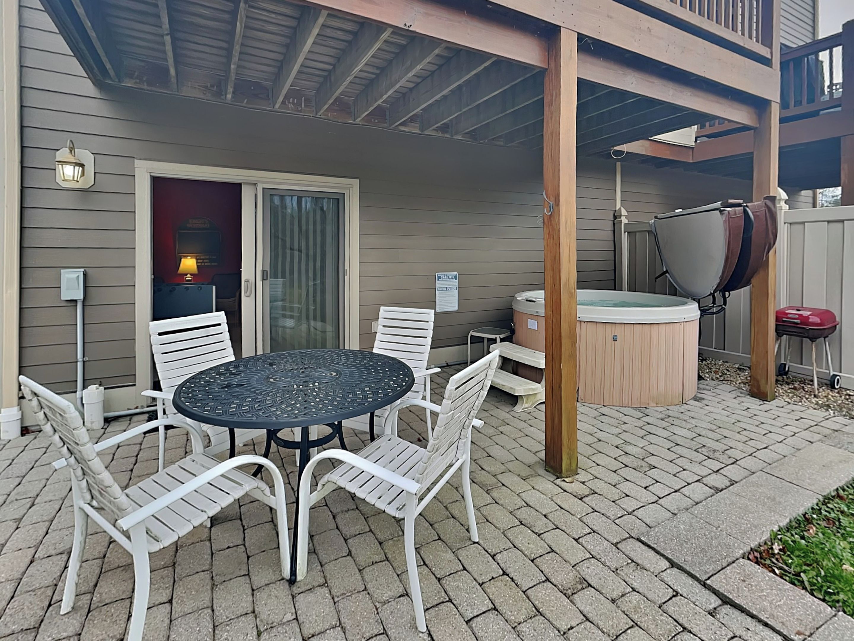 Een terras met een ronde tafel en witte stoelen, een jacuzzi en een overdekt gebied met een houten terras.