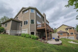 A two-story house with a covered patio, a chimney, and a small deck.