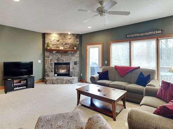 A living room with a stone fireplace, a television, a sofa, and a coffee table.