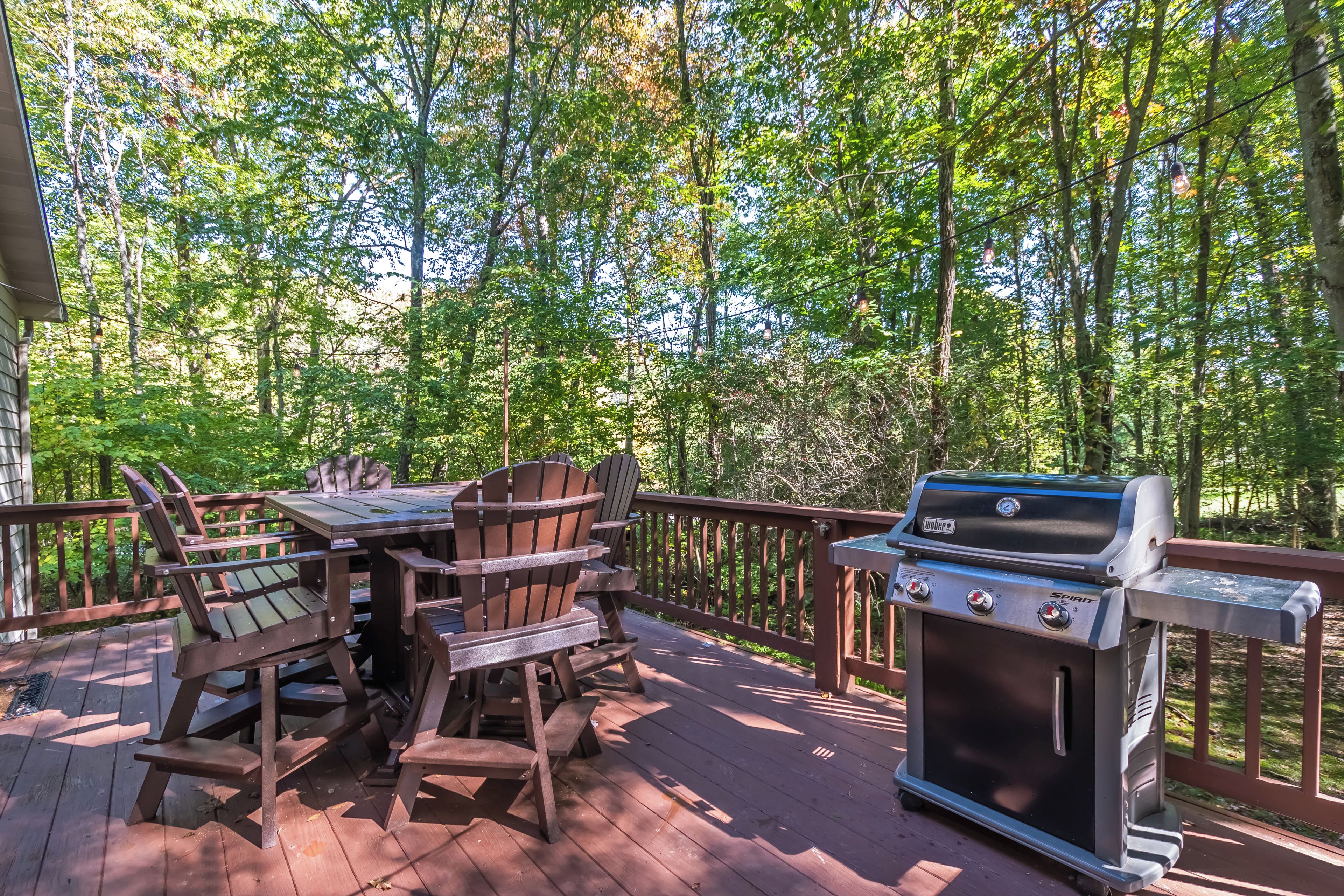 Eine Holzterrasse mit Grill und Gartenmöbeln.