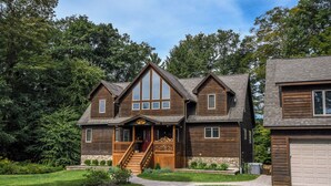 A two-story wooden house with a front porch, a staircase, and a garage. - Midnight Dip by Taylor Made Deep Creek (Swanton)