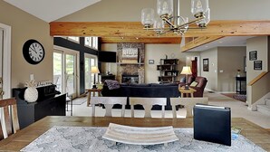 A spacious living area with a dining table, a fireplace, and a chandelier. - Million Dollar View by Taylor Made Deep Creek (McHenry)