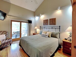 Ein Schlafzimmer mit einem Bett, einem Sessel, einem Schreibtisch, einer Lampe und einem Fernseher.
