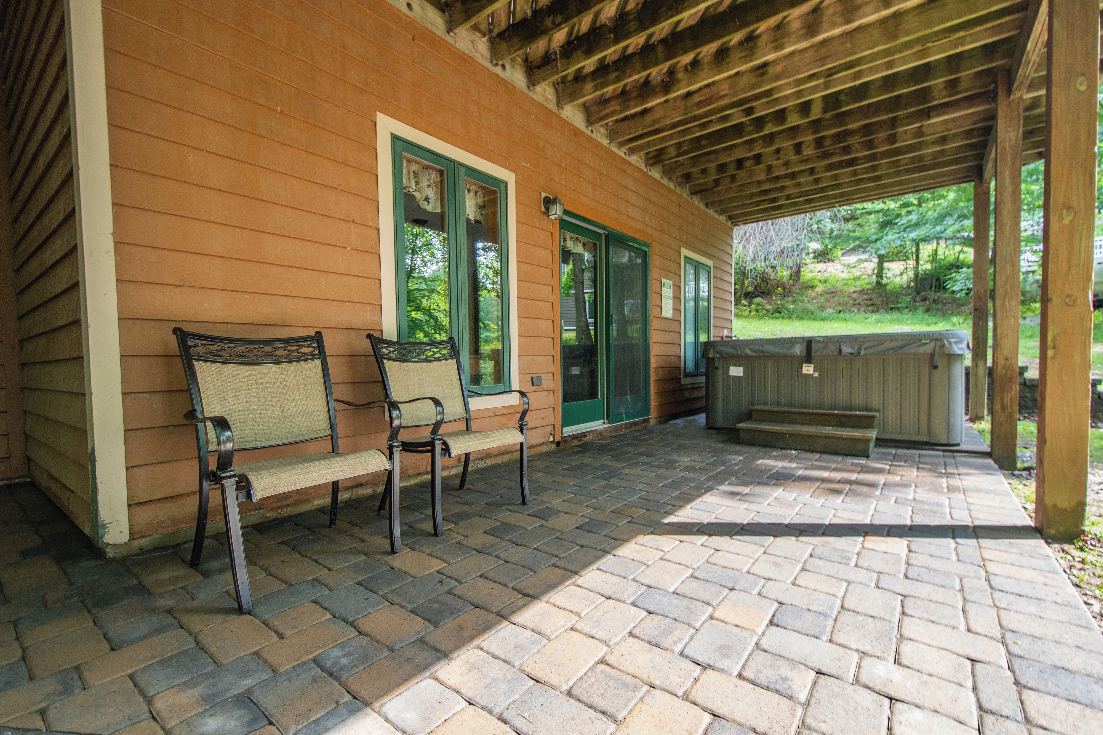 A covered patio with two chairs and a grill area.