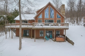 A two-story house with a balcony, large windows, and a stone chimney.