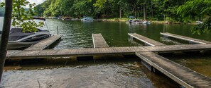 A wooden dock extending into a calm lake surrounded by dense forest. - Misty Creek by Taylor Made Deep Creek (McHenry)