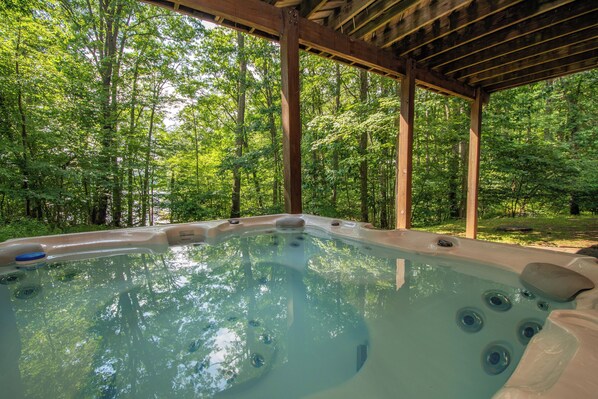 A hot tub in a forested area with a wooden pergola overhead. - Misty Creek by Taylor Made Deep Creek (McHenry)