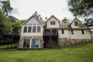 A two-story house with a stone foundation, a balcony, and a flag.