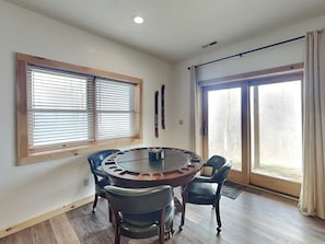 A dining area with a round table and four chairs, large windows with blinds, and a sliding glass door. - Moonlight Ridge by Taylor Made Deep Creek (McHenry)