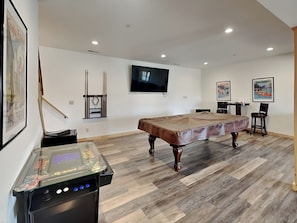 A spacious room with a pool table, a mounted TV, and a bar area. - Moonlight Ridge by Taylor Made Deep Creek (McHenry)