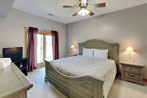 A bedroom with a bed, bedside lamps, a television, and a ceiling fan. - Moonrise Retreat by Taylor Made Deep Creek (Swanton)