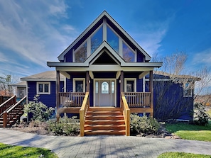 A two-story house with a front porch, a staircase leading to the entrance, and a well-maintained lawn.