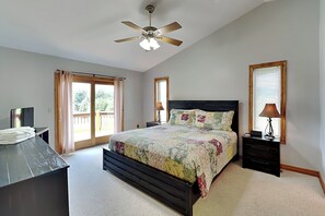A bedroom with a bed, a desk, a ceiling fan, and a window with curtains.