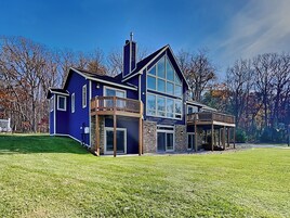 A modern two-story house with a large glass window, a balcony, and a stone facade.