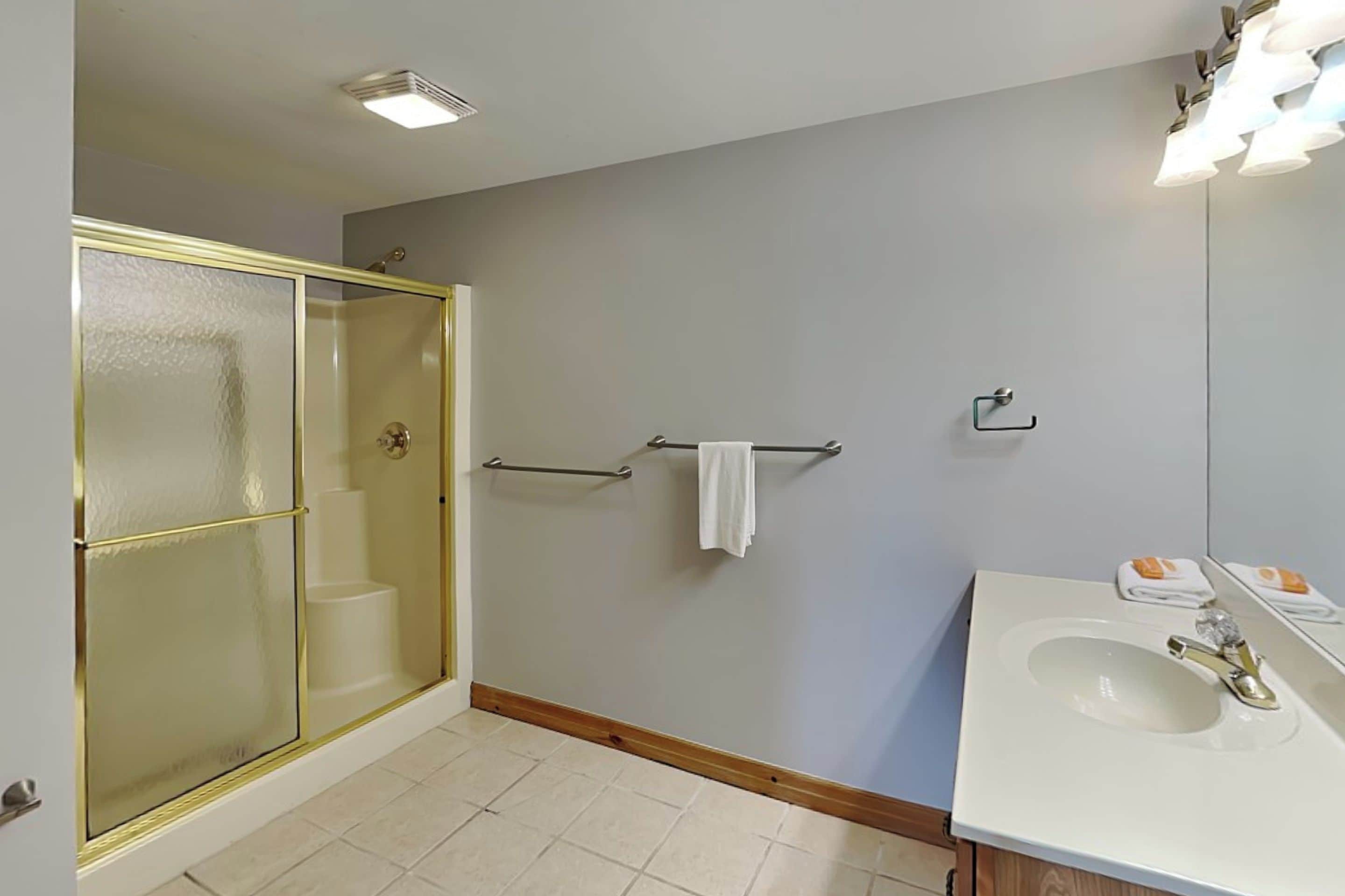 A bathroom with a shower, a sink, and a mirror.