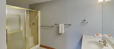 A bathroom with a shower, a sink, and a mirror.