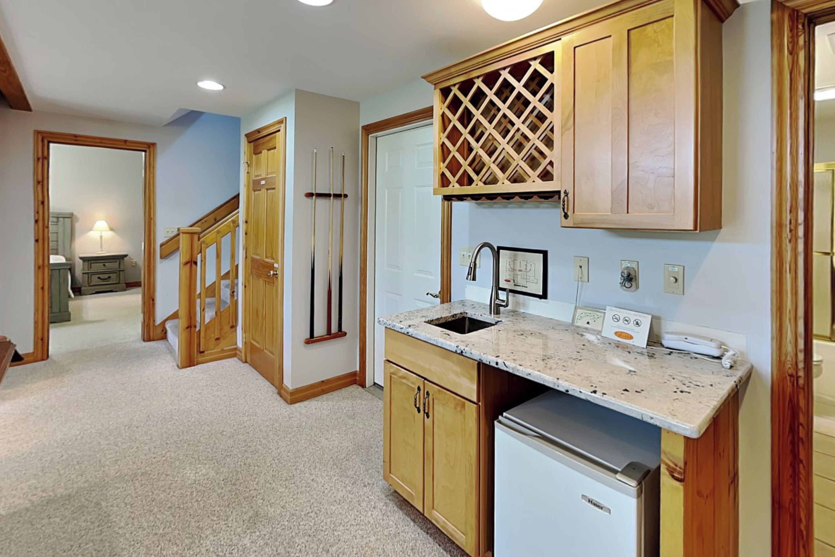 A kitchen with wooden cabinets, a stainless steel refrigerator, and a marble countertop.