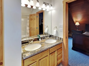 A bathroom with a double sink, wooden cabinets, a large mirror, and a ceiling light fixture. - Mountain Dreams by Taylor Made Deep Creek (McHenry)