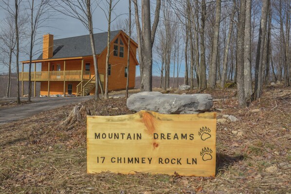 Una cabaña de madera con balcón, identificada como "Mountain Dreams 17 Chimney Rock Ln".