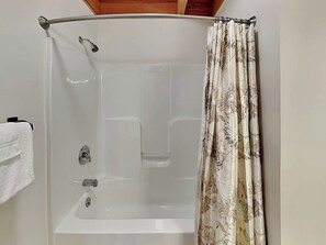 Cabina de ducha con puerta de cristal, ducha y cortina.