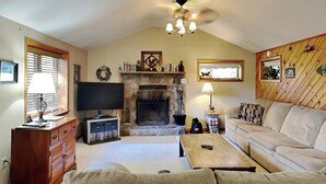 A cozy living room with a fireplace, a television, a sofa, and a coffee table. - Mountain Escape by Taylor Made Deep Creek (McHenry)