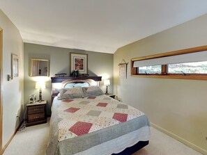 A bedroom with a bed, two bedside tables, a window with a view, and a headboard with a mirror and framed pictures. - Mountain Escape by Taylor Made Deep Creek (McHenry)