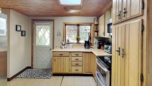 A kitchen with wooden cabinets, a built-in oven, and a skylight. - Mountain Escape by Taylor Made Deep Creek (McHenry)
