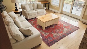 A living room with a beige sectional sofa, a wooden coffee table, and a red patterned rug. - Mountain Splendor by Taylor Made Deep Creek (Swanton)