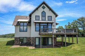 A two-story house with a balcony and a stone foundation. - Mountain Splendor by Taylor Made Deep Creek (Swanton)