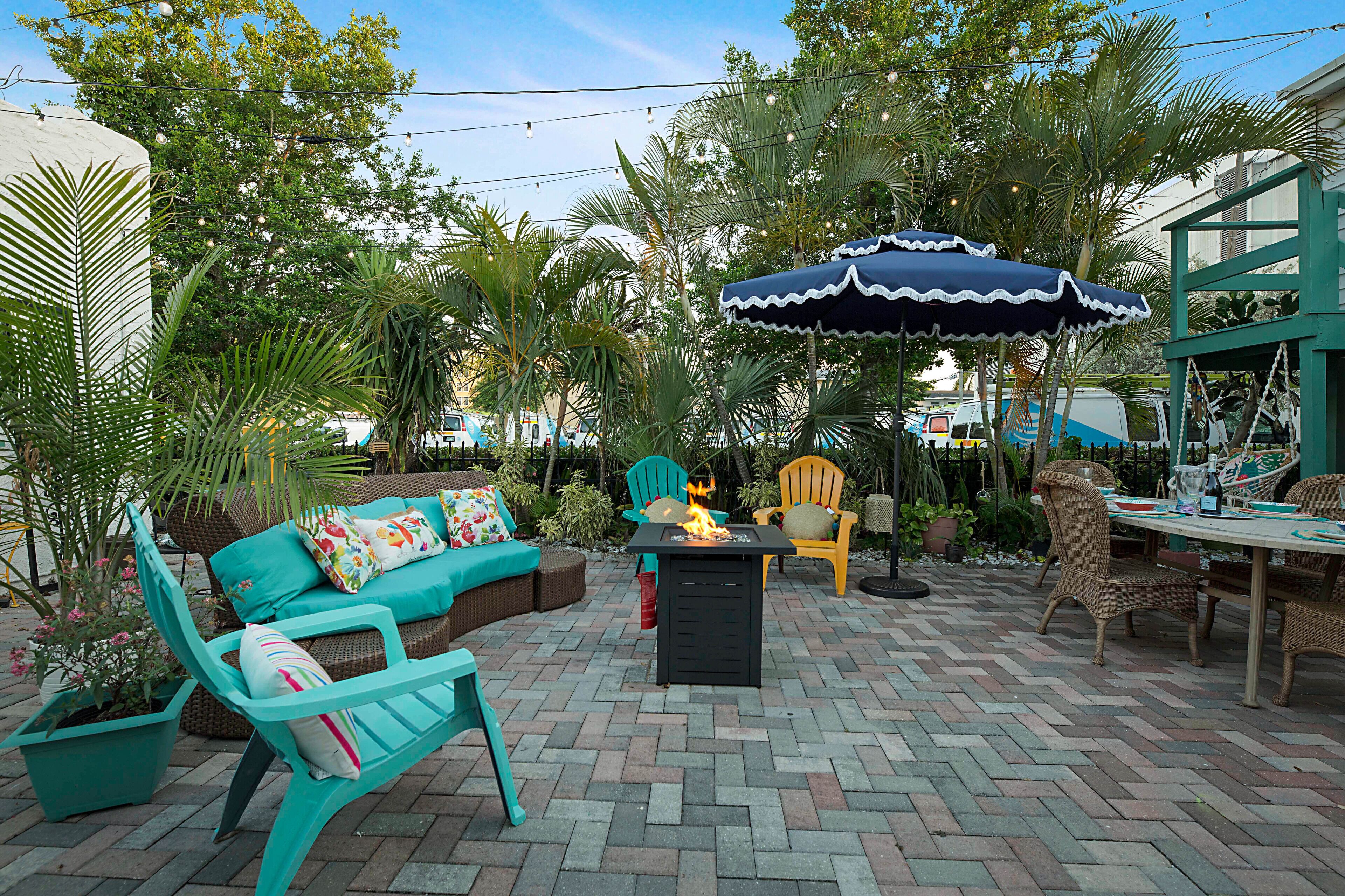 An outdoor patio with a fire table, seating area, and umbrellas.