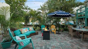 An outdoor patio with a fire table, seating area, and umbrellas.