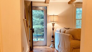 A hallway with wooden flooring, a door leading outside, a lamp, and a sofa. -  BRAND NEW KITCHEN! CLOSE TO DOWNTOWN EDGARTOWN AND THE BEACH! (Edgartown)