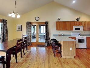 A kitchen with wooden cabinets, a microwave, a stove, and a dining area with a table and chairs.