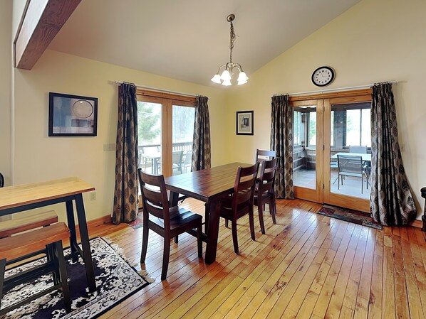 A dining area with a wooden table and chairs, a chandelier, and a clock on the wall.