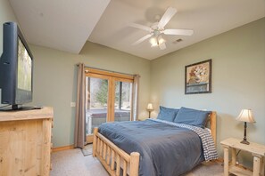 A bedroom with a bed, a television on a wooden desk, a ceiling fan, and a window with curtains. - Mountain Top Lodge by Taylor Made Deep Creek (McHenry)