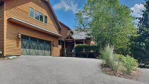 A two-story wooden house with a garage, a covered porch, and a landscaped front yard. - Mountainlair by Taylor Made Deep Creek (McHenry)