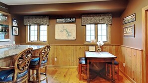 A kitchen with wooden paneling, a bar area with stools, a map on the wall, and a sign indicating 'Lake'. - Mountainlair by Taylor Made Deep Creek (McHenry)