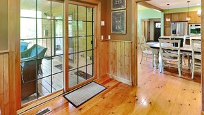 A wooden interior with a ski lift sign, a dining area with white chairs, and a kitchen with wooden cabinets. - Mountainlair by Taylor Made Deep Creek (McHenry)