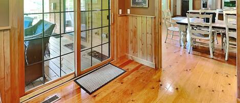 A wooden interior with a ski lift sign, a dining area with white chairs, and a kitchen with wooden cabinets.