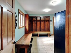 A kitchen with wooden cabinets, a wooden bench, a refrigerator, and a window. - Mountainlair by Taylor Made Deep Creek (McHenry)