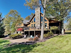 A large, two-story stone building with a balcony and outdoor seating area. - Mountainlair by Taylor Made Deep Creek (McHenry)