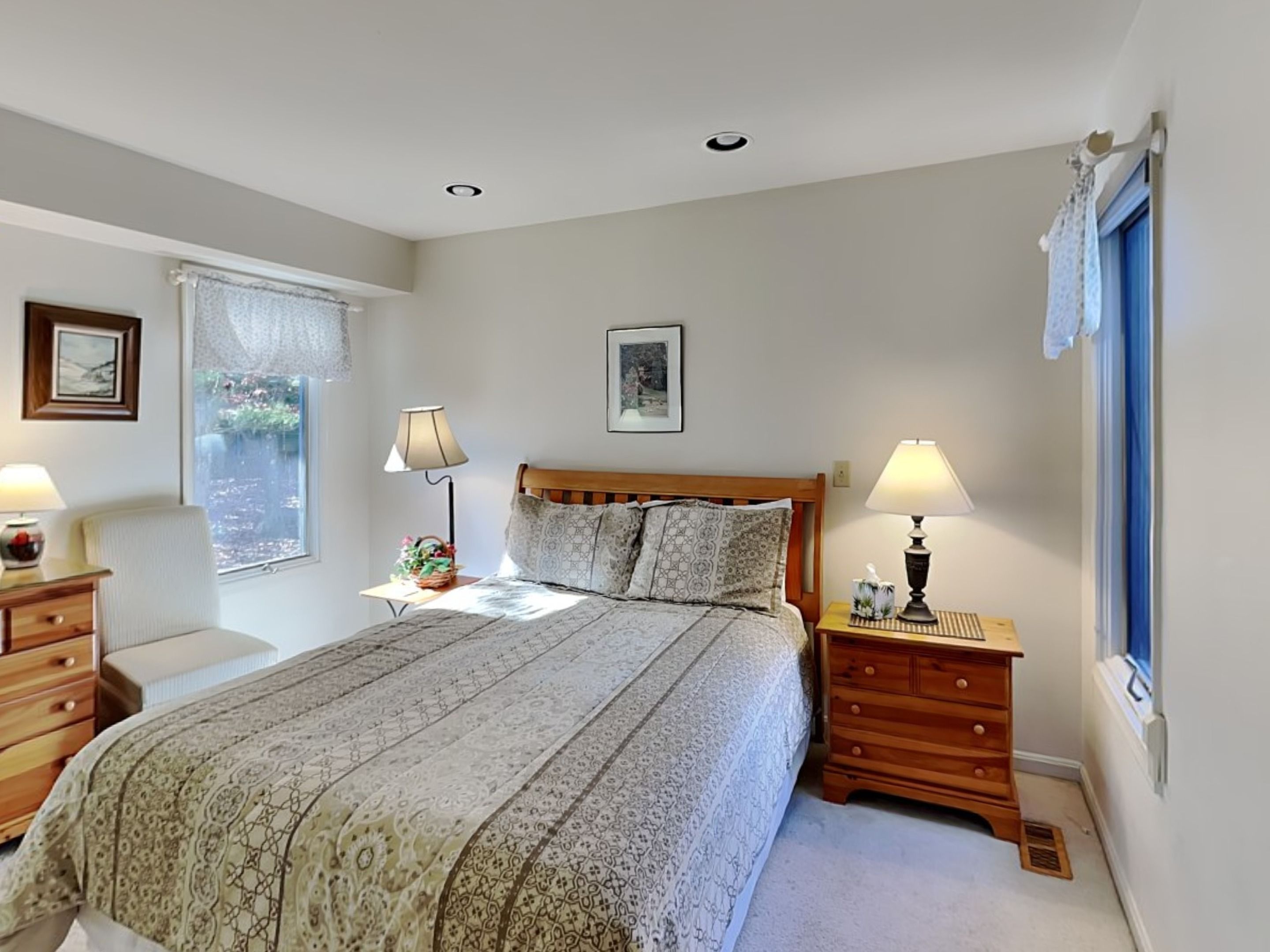 A bedroom with a large bed, two bedside tables, a window with a view, and a ceiling light.