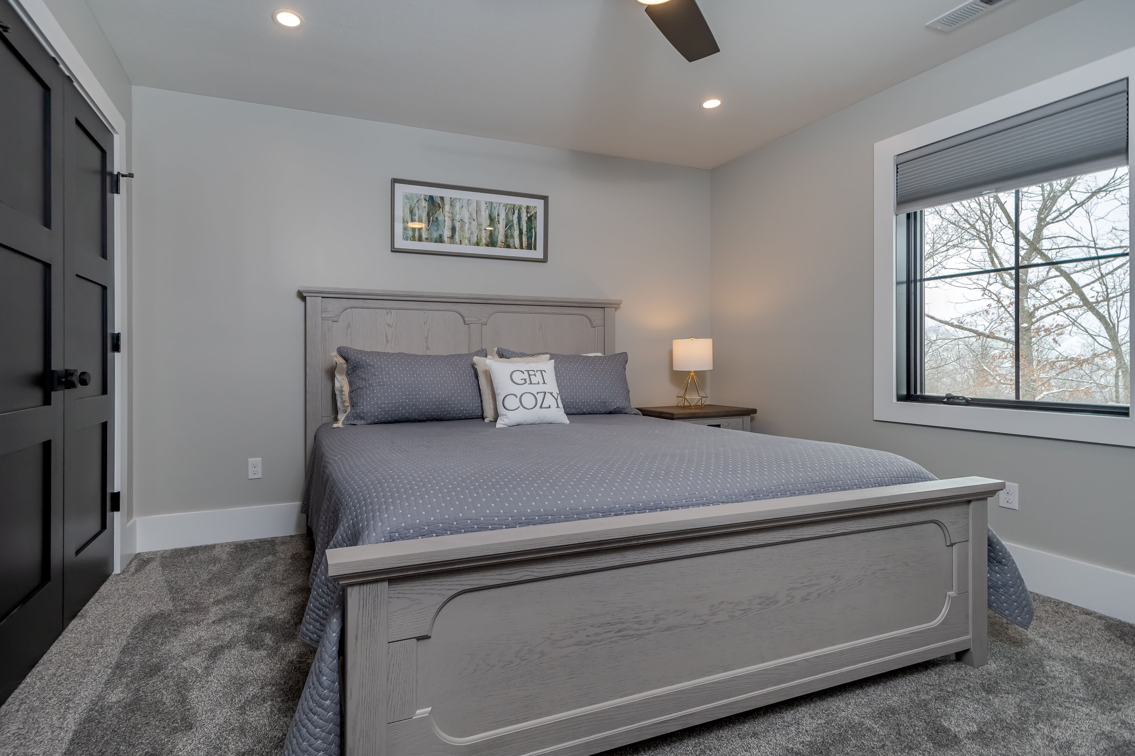 A bedroom with a bed, a nightstand, a window, and a ceiling fan.