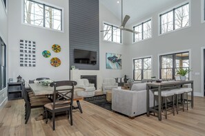 A spacious living area with a dining table, sofas, and a fireplace. - No Black Tie Affair by Taylor Made Deep Creek (McHenry)